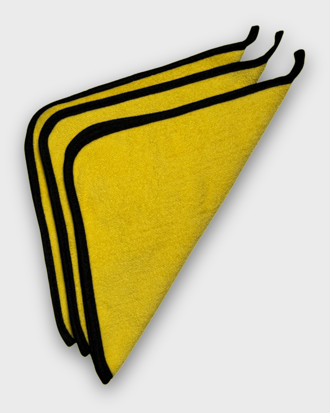 Three yellow microfiber cleaning towels with black trim, stacked and folded diagonally on a light gray background.
