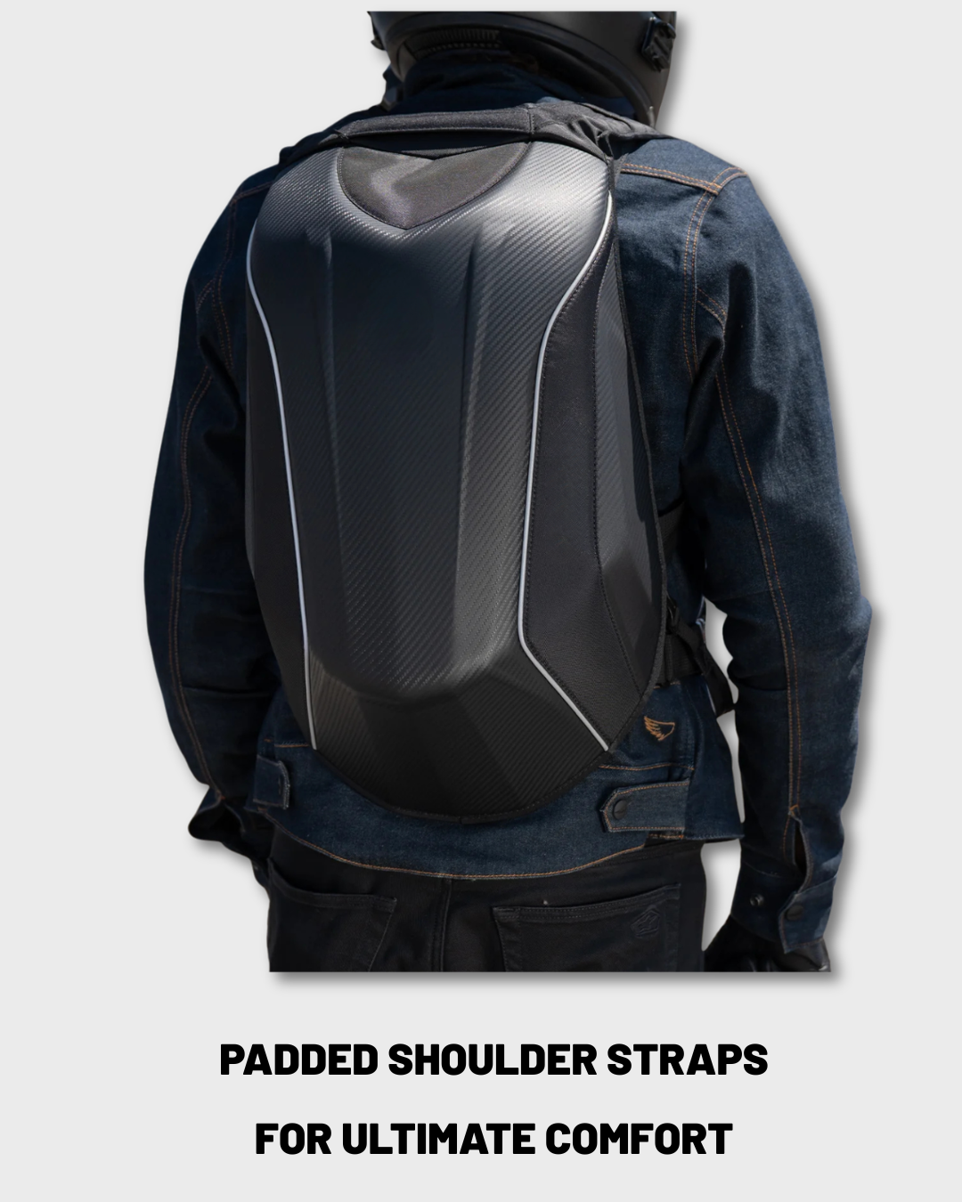 A person shown from the back wearing a hard shell helmet holding motorcycle backpack over a blue denim jacket, with text at the bottom reading 'PADDED SHOULDER STRAPS FOR ULTIMATE COMFORT'