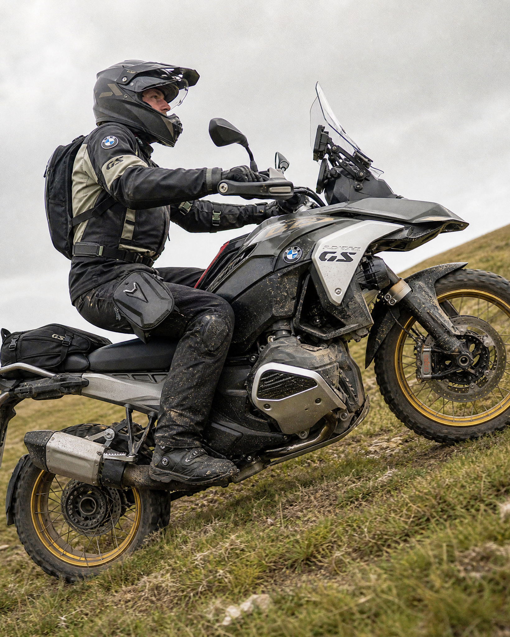 Person riding a BMW motorcycle on a grassy hillside wearing a waterproof motorcycle leg bag
