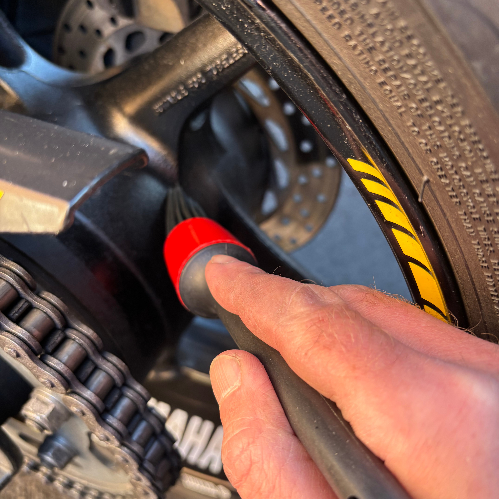 Person using a Ride It Rite detailing brush cleaning a motorbike wheel