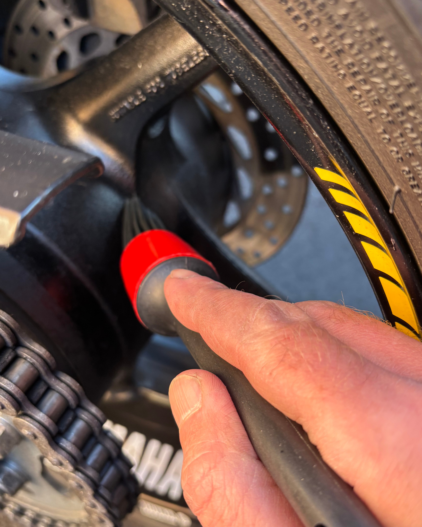 Person using a Ride It Rite detailing brush cleaning a motorbike wheel