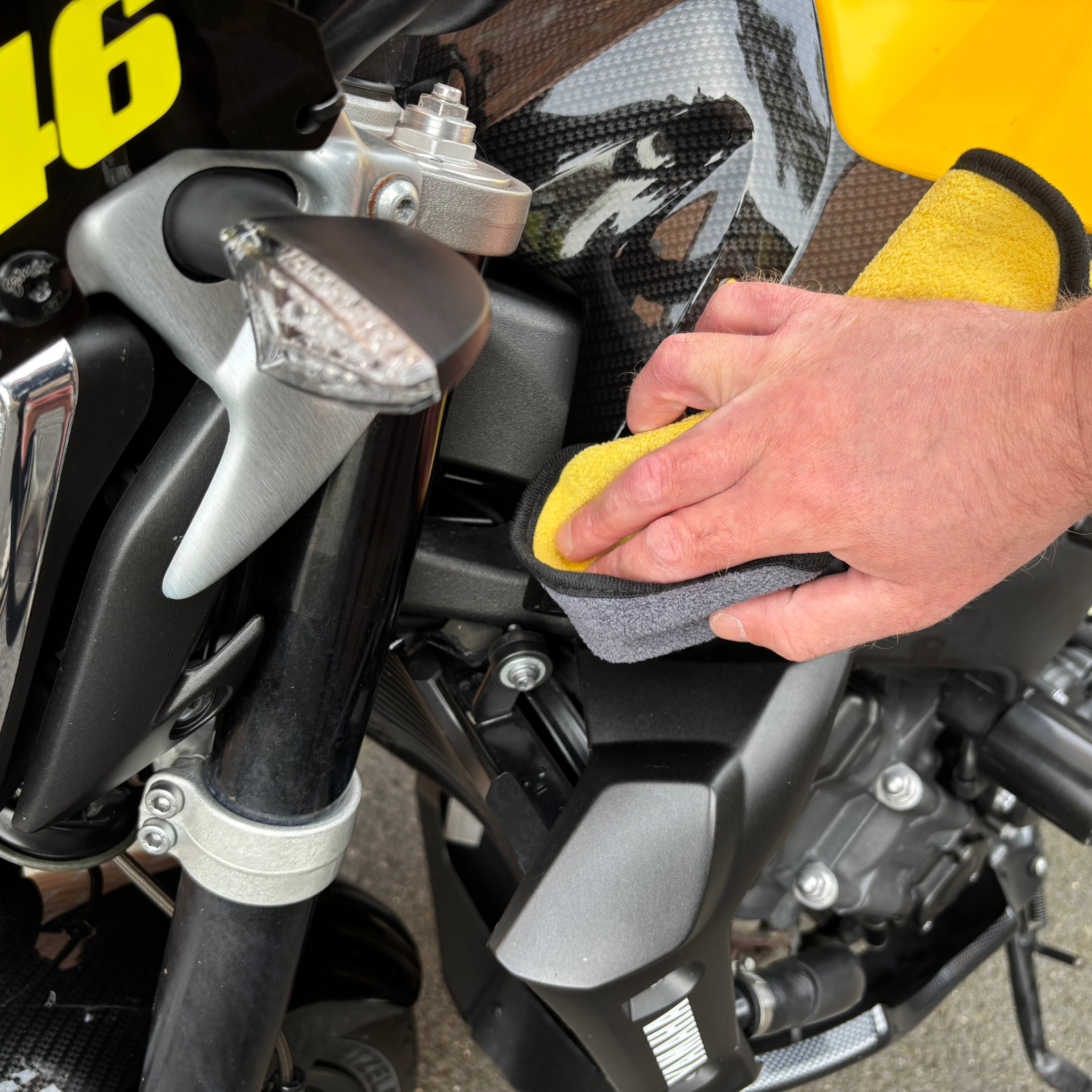 Person cleaning a motorcycle with a yellow Ride It Rite cloth.