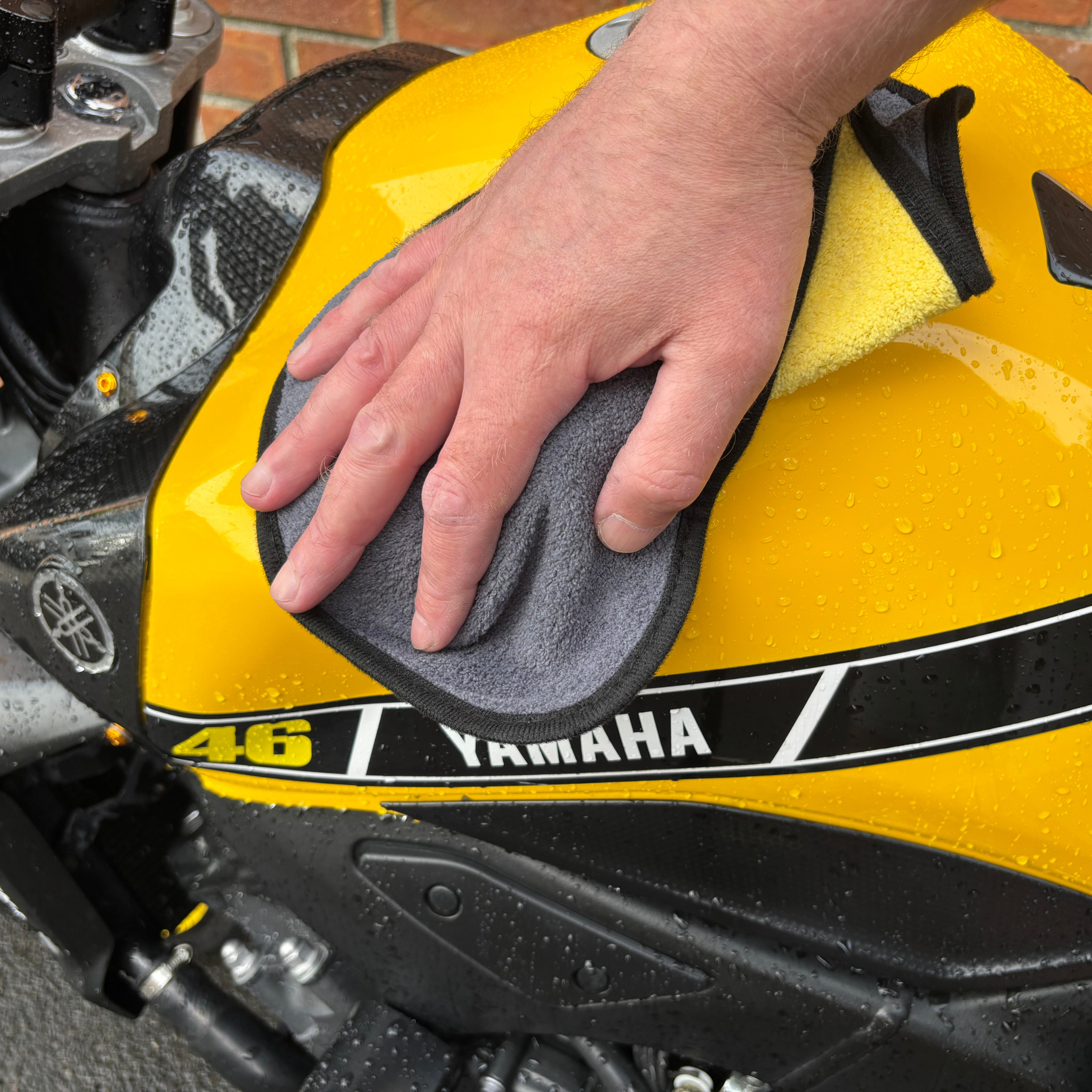Person cleaning a yellow Yamaha motorcycle with a Ride It Rite cloth. cloth.