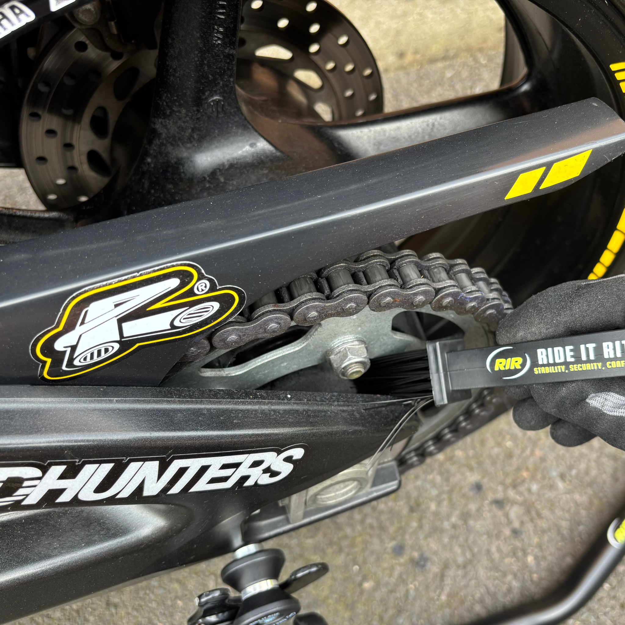 Close-up of a motorcycle chain and sprocket being cleaned with a Ride It Rite chain cleaning brush.