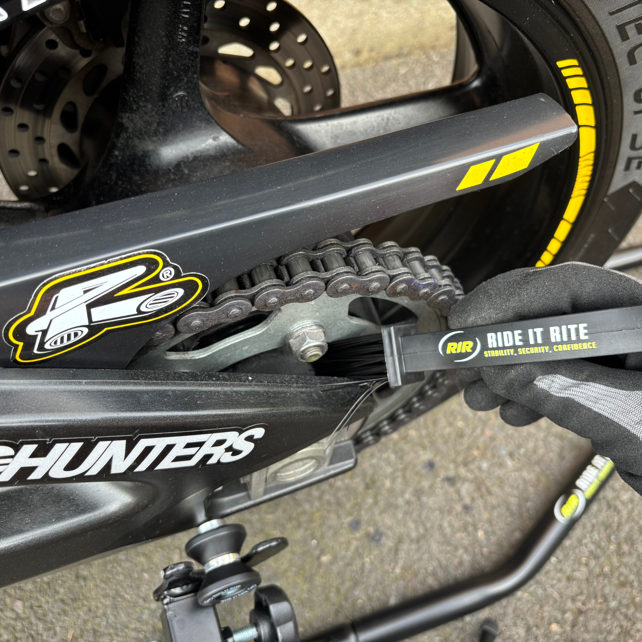 Close-up of a motorcycle on Ride It Rite black rear paddock stand, chain and sprocket cleaned with Ride It rite Chain cleaning brush.