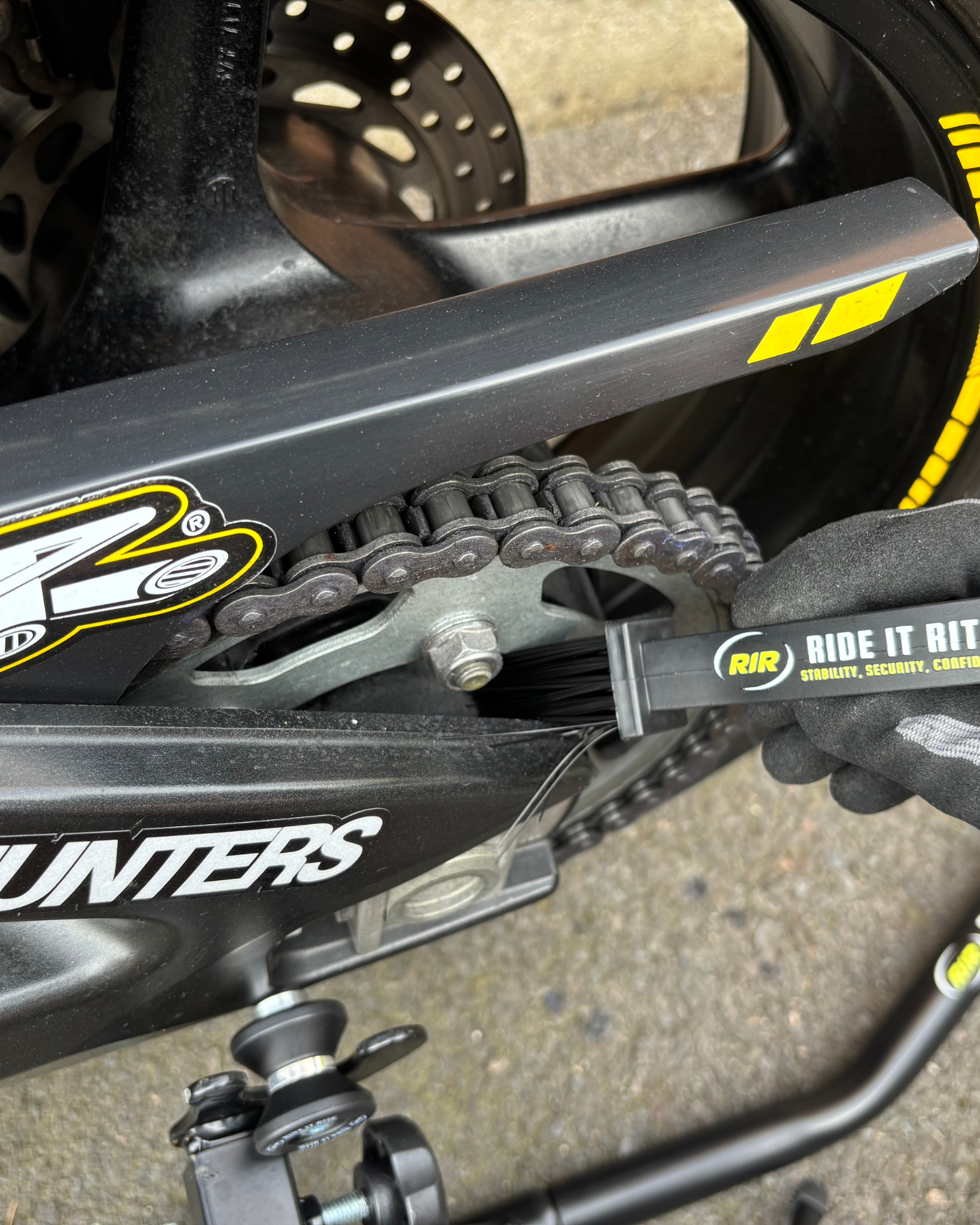 Close-up of a motorcycle on Ride It Rite black rear paddock stand, chain and sprocket cleaned with Ride It rite Chain cleaning brush.