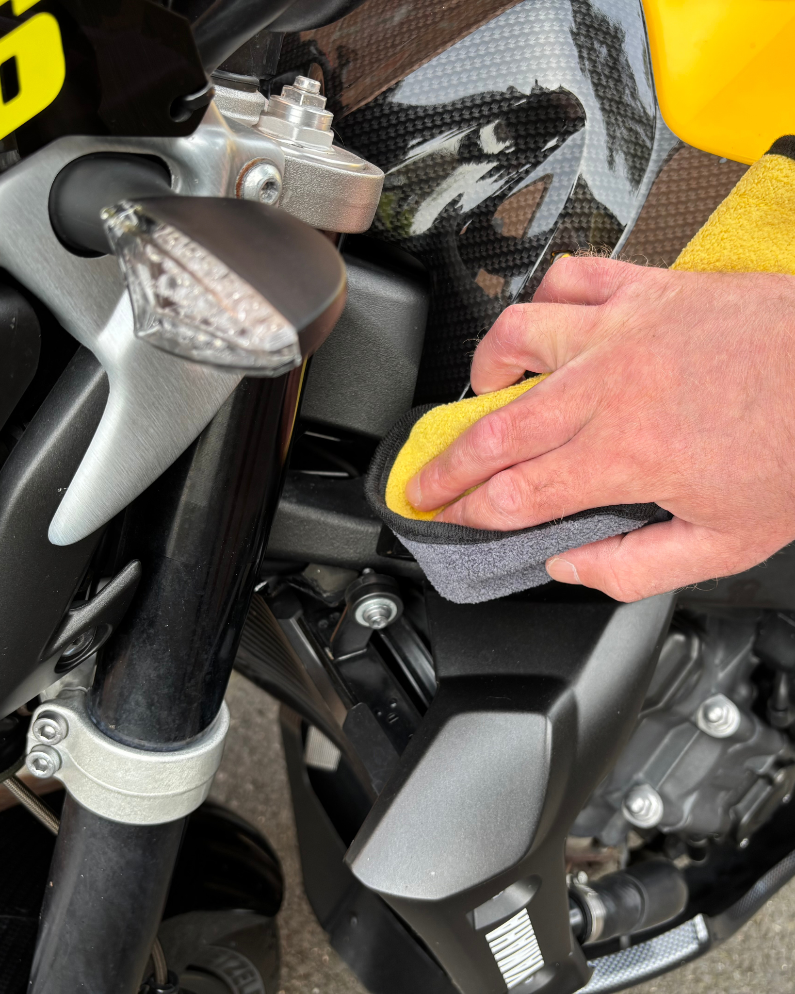 Person cleaning a motorcycle with a yellow Ride It Rite cloth.