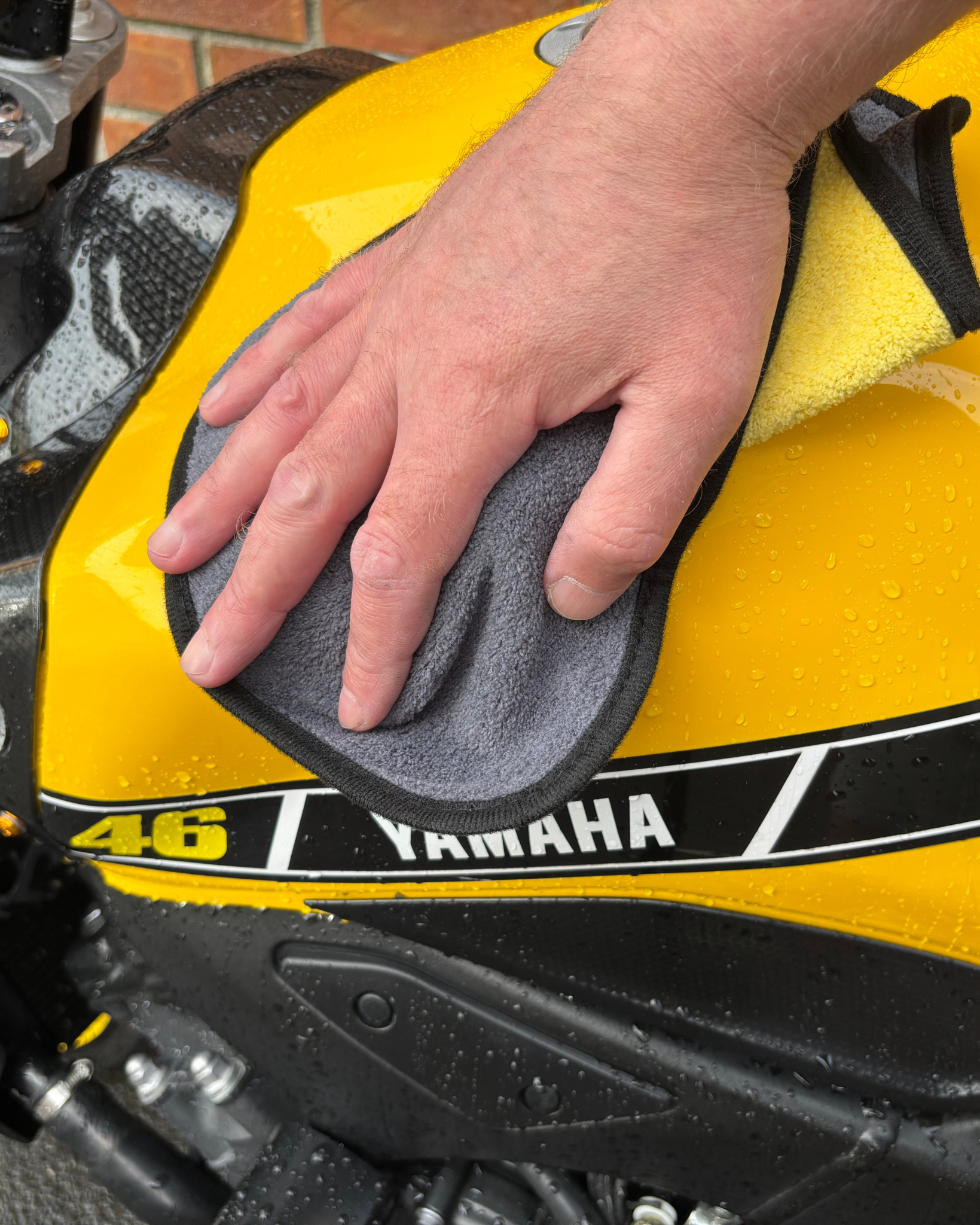 Person cleaning a yellow Yamaha motorcycle with a Ride It Rite cloth. cloth.